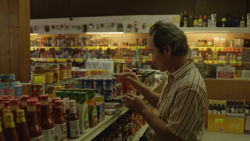 A man stocks cans on a shelf in a store