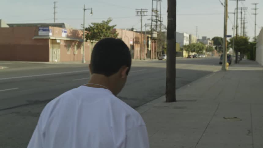 A man walks down the sidewalk on a sunny day