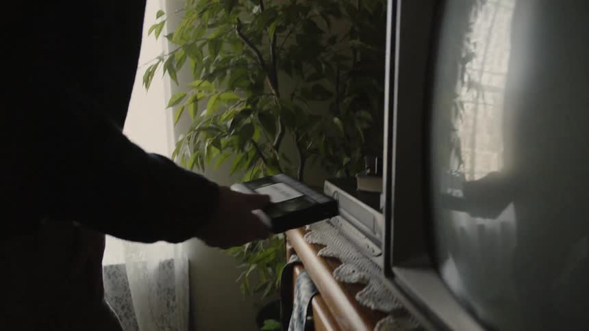 The man gets up to place a tape in the vcr