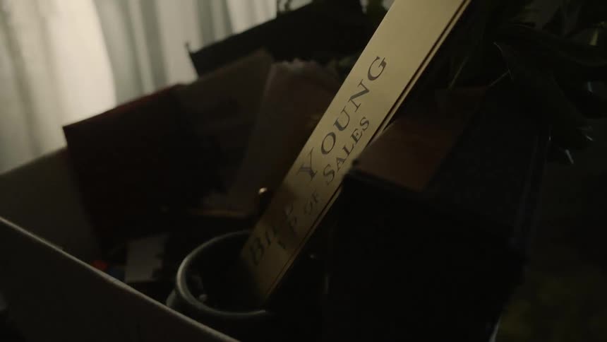 A person's office belongings sit in a cardboard box