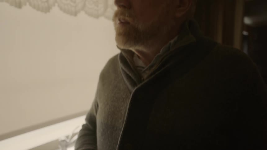 A man holds his mug looking towards a window