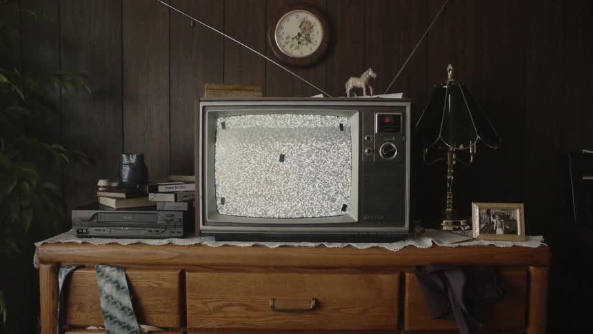 The small television is flickering on the dresser