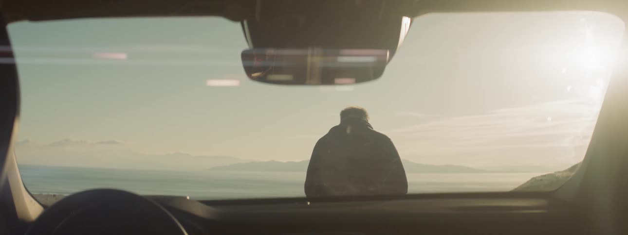Two men stand outside a vehicle on a sunny day