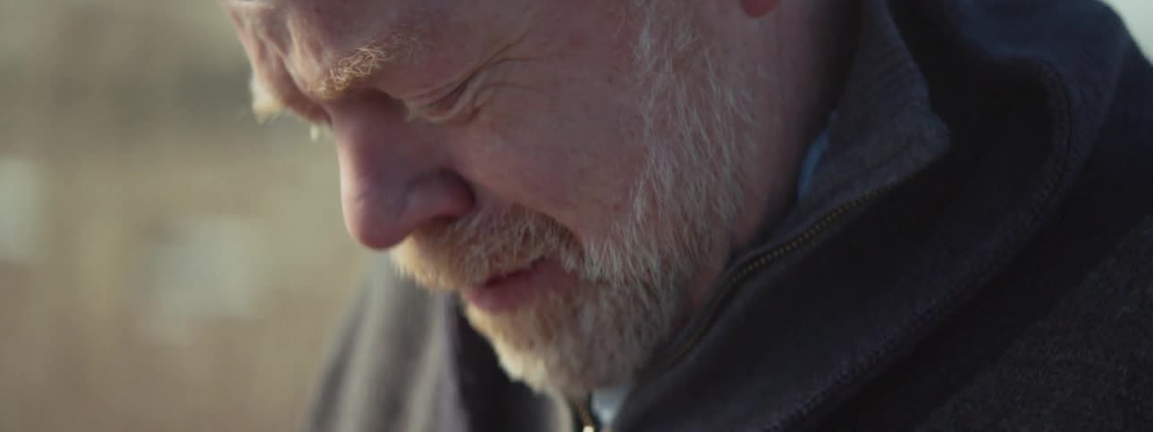Elderly man cries as he looks down at pictures