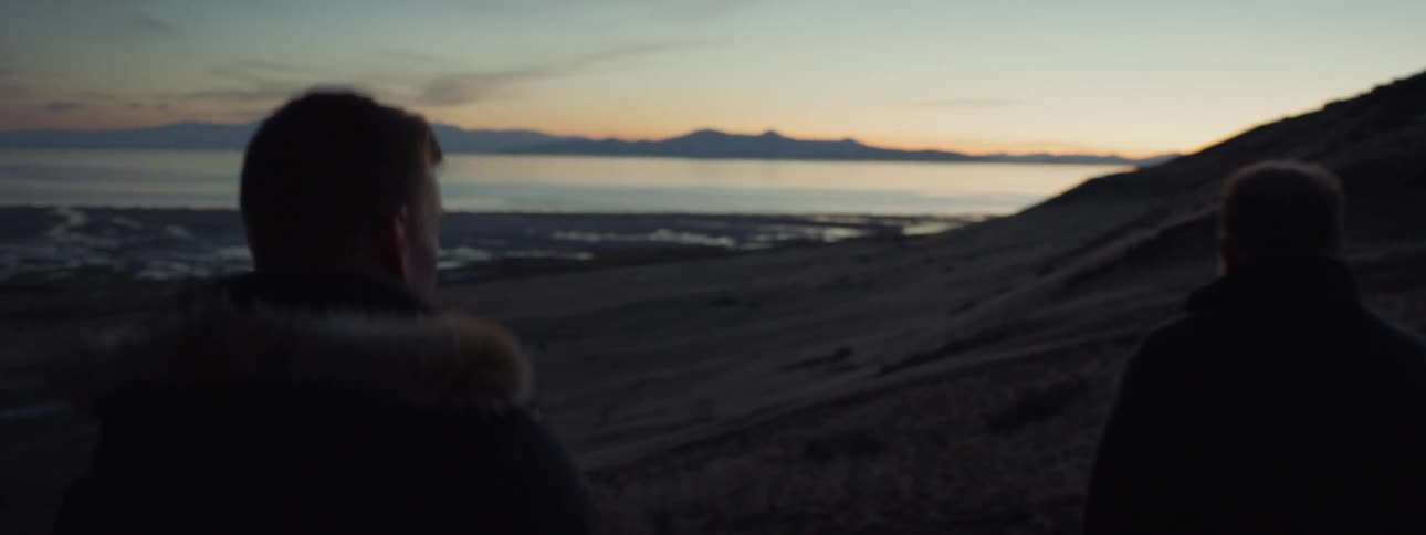 Two men walk on the beach at sunset