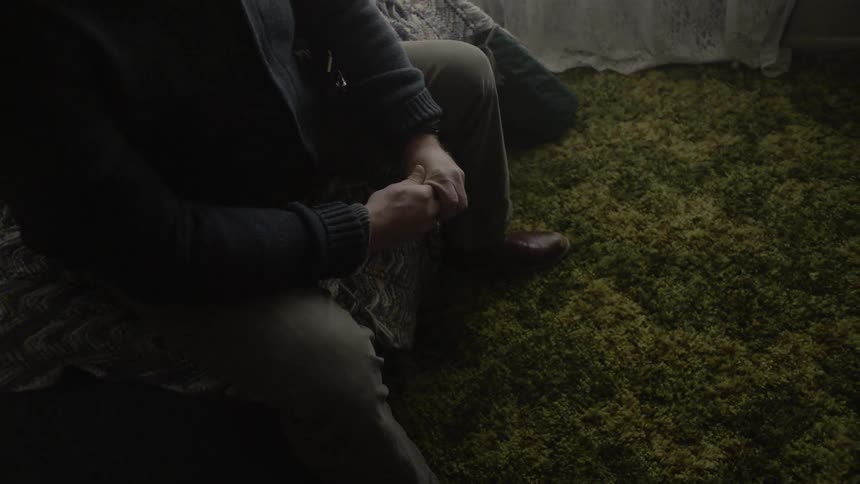 A man sits on his bed in the room
