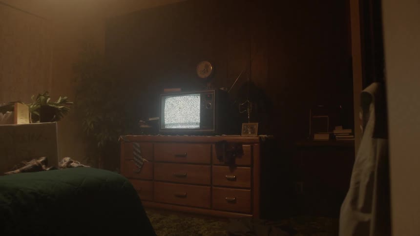 The television in the dark bedroom is flickering