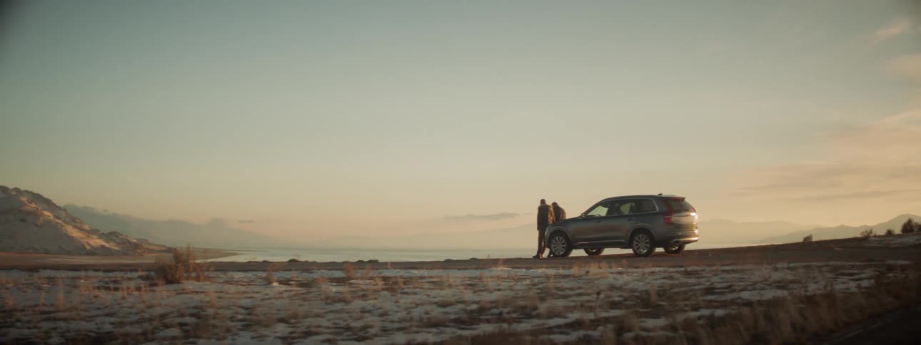 Two people stand near the vehicle ahead