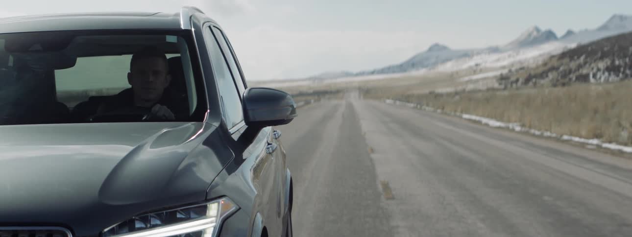 A man drives his black car on the road