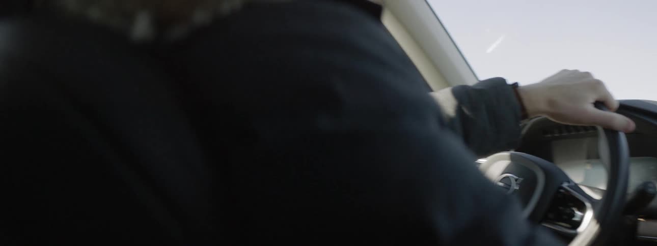 A man sits in the car steering as he drives