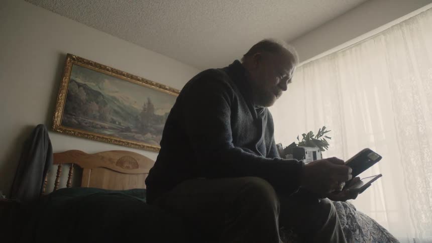 A man looks at a photograph sitting in his bed