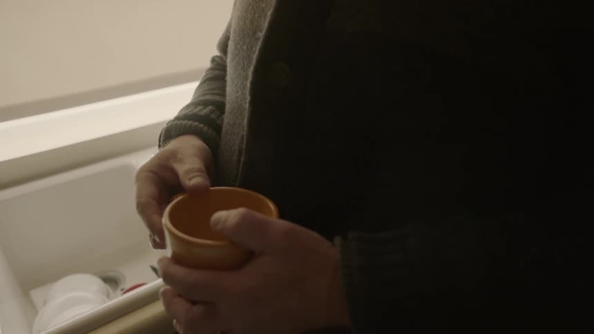 A man looks towards the window holding his mug