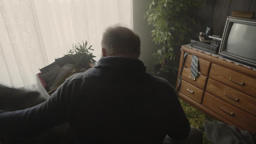 Man looks through a box of belongings while sitting on a bed