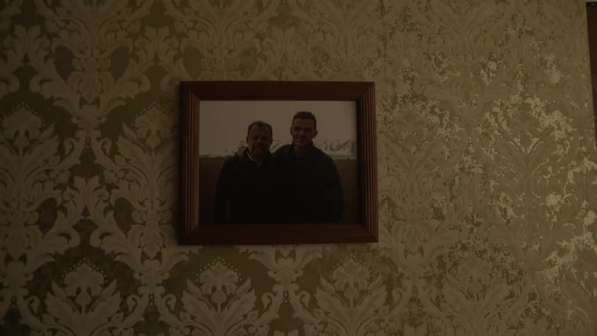 A framed photograph of two men hangs on a wall