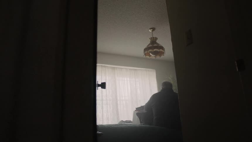 Man sits on a bed taking things out of a box