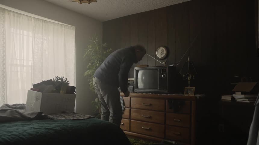 Man turns on an old television in a bedroom