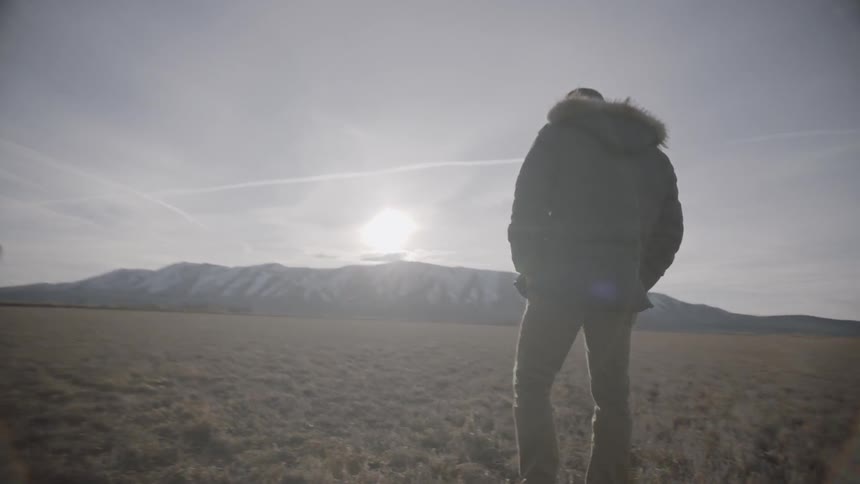 Two men stand in a field on a sunny day