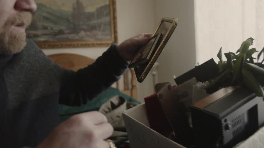 A man lifts some photographs from a cardboard box