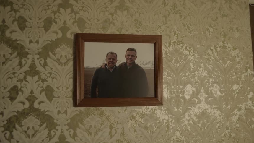A photo of two men is hung on the wall