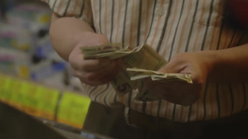 Man counts money at a cash register