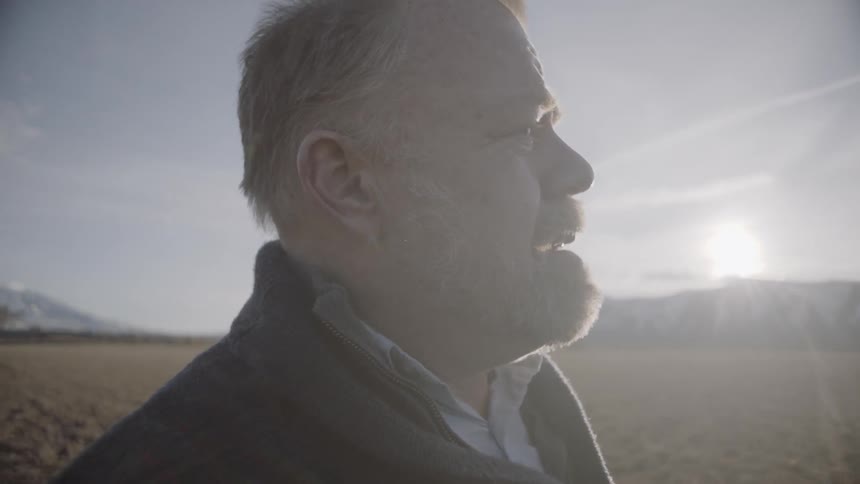 A man talks while standing on the field at sunset