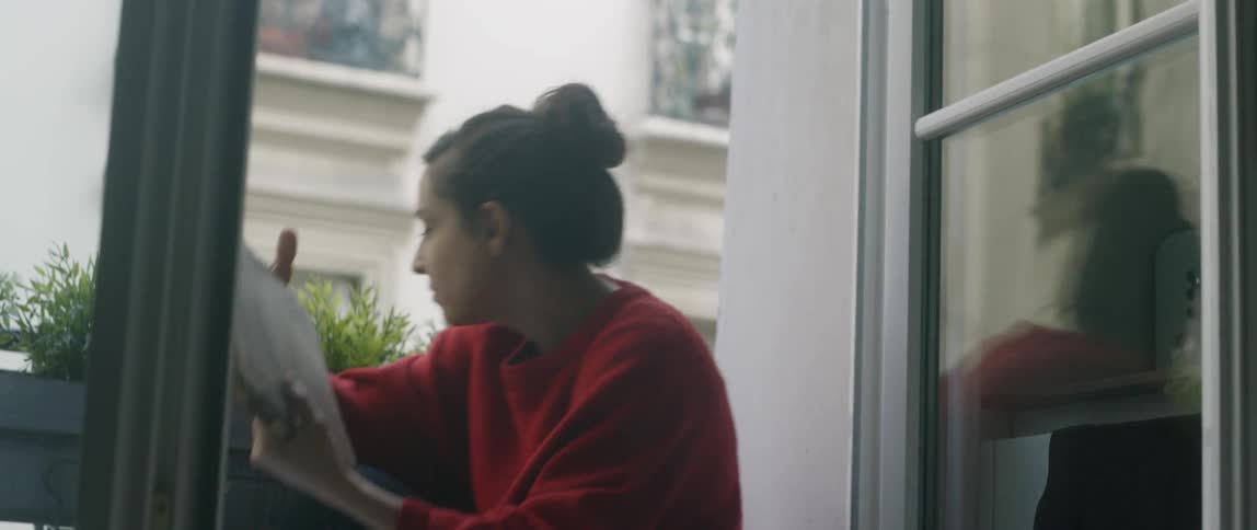 A woman sits by her window terrace reading a book