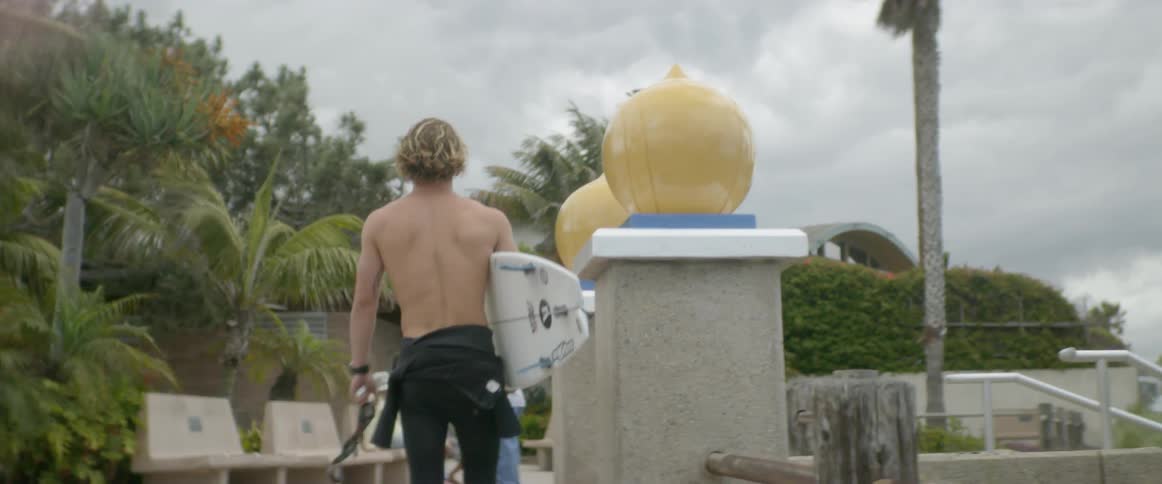 Man carries a surfboard onto a beach