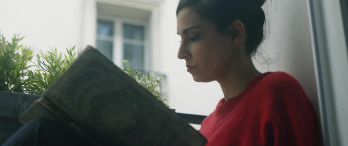 Woman reads on an apartment balcony