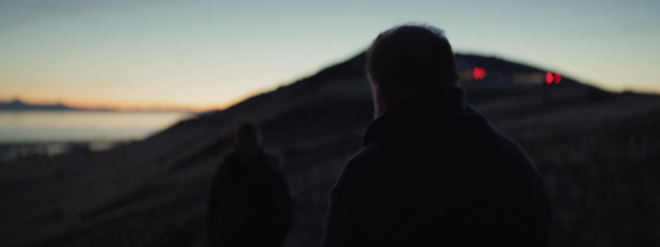 Two men slowly walk towards the beach at dawn