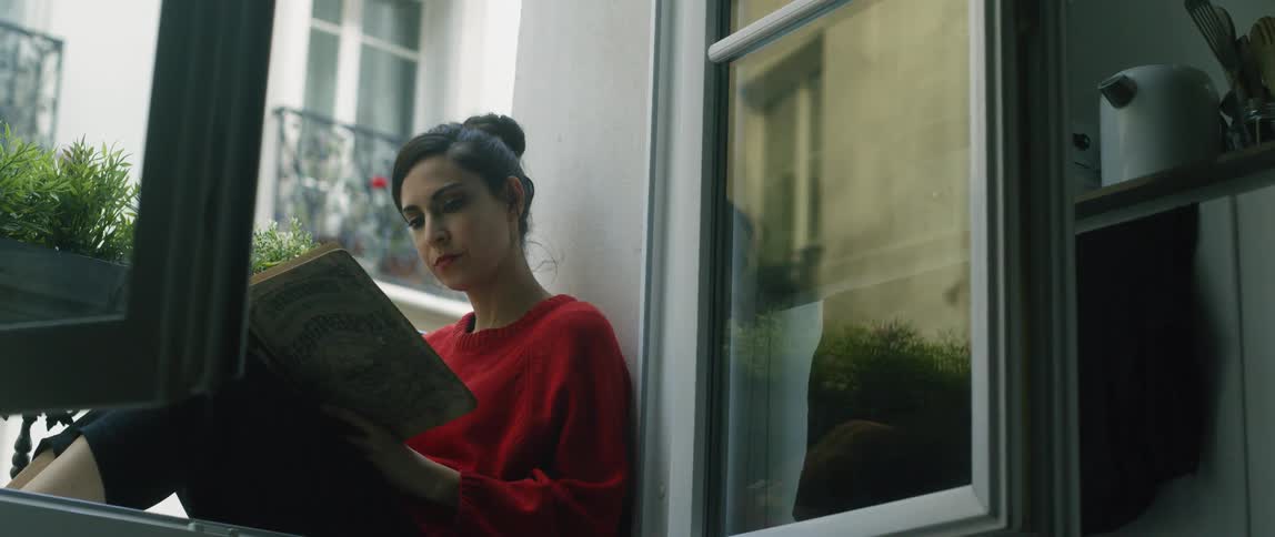 Woman sits reading a book on a balcony
