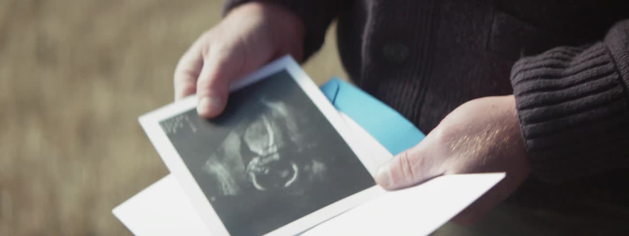 Man opens a card with an ultrasound of a baby