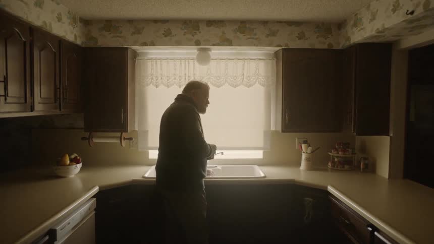 Man leans over a kitchen sink and turns to the side