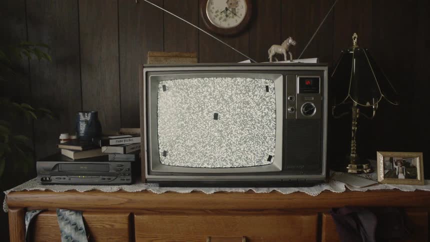 Five small pieces of black tape attached to a television screen as static flickers on the screen