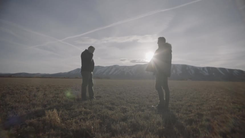 Two people stand on the field together talking