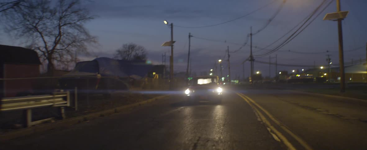 A car drives down a deserted city street at night