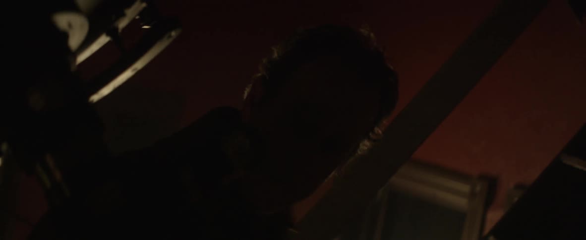 Man moving around and looking through a scope in a dark room