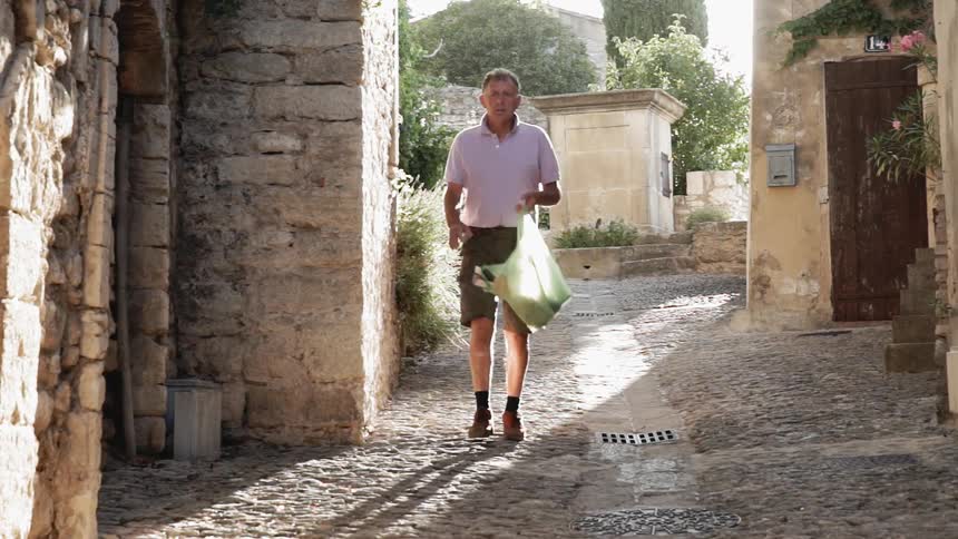 Man carrying a grocery bag walks down an alleyway