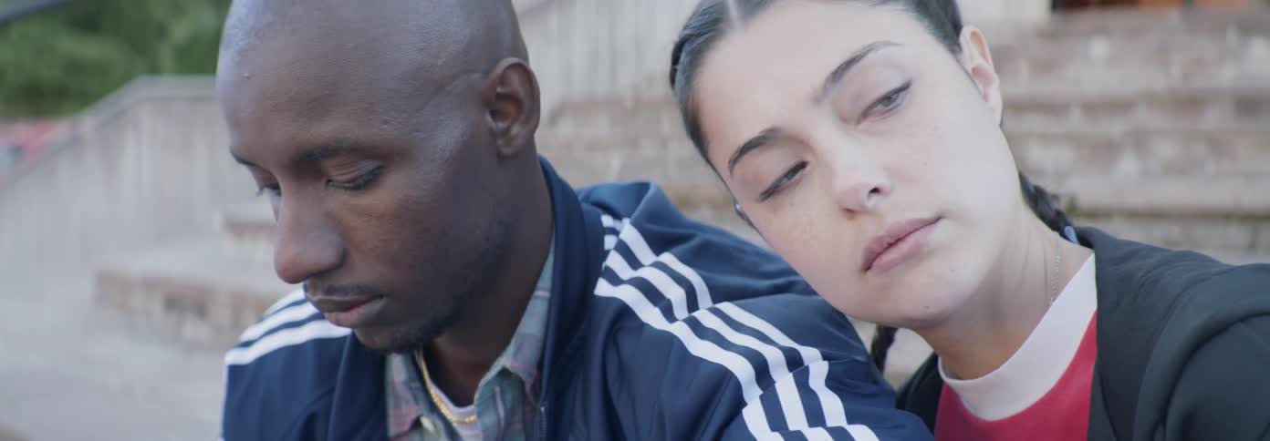 A woman leans on a man's shoulder briefly