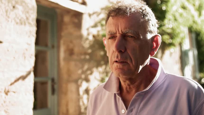 Elderly man stands outside on a sunny day