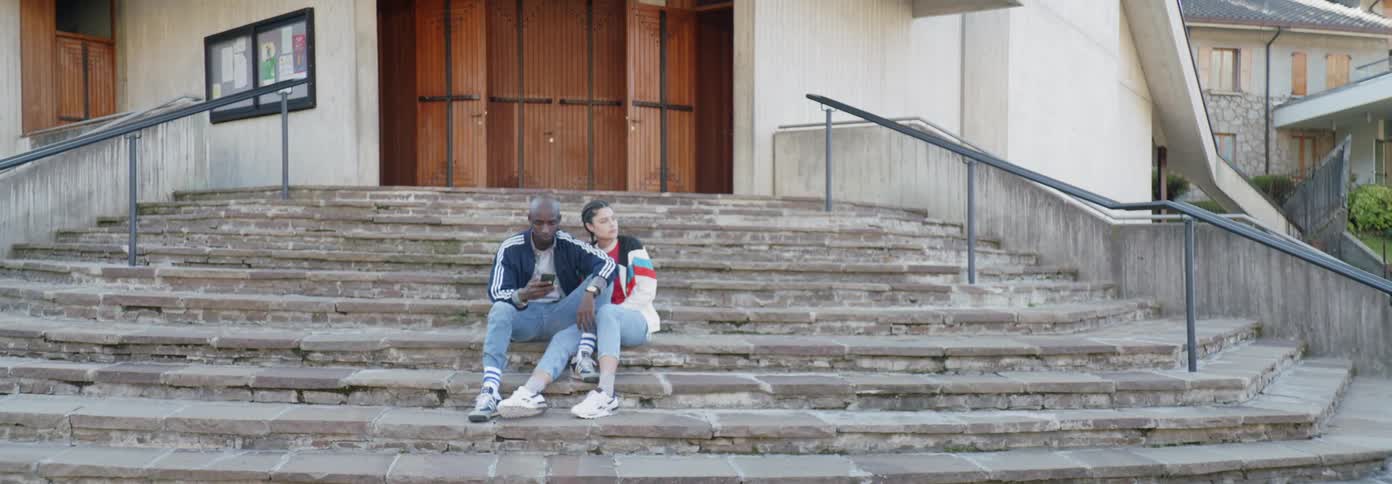 A woman leans on a man sitting on the steps