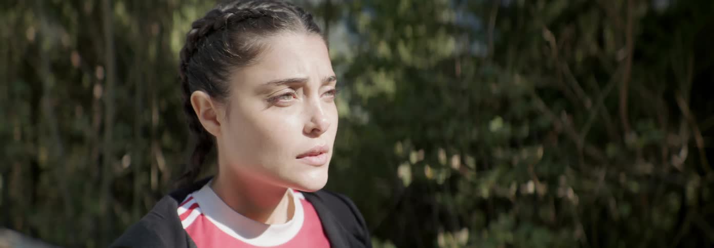 A woman looks sad outside near trees