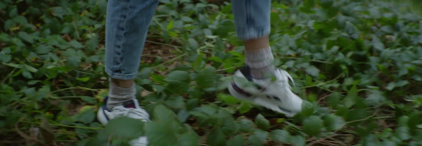 A woman walks backwards through the vines