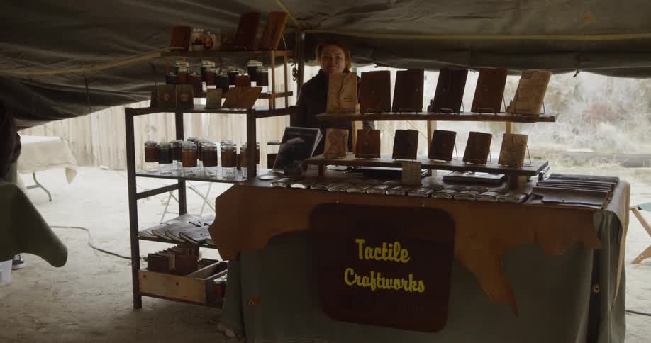 A woman is working a stand under the tent