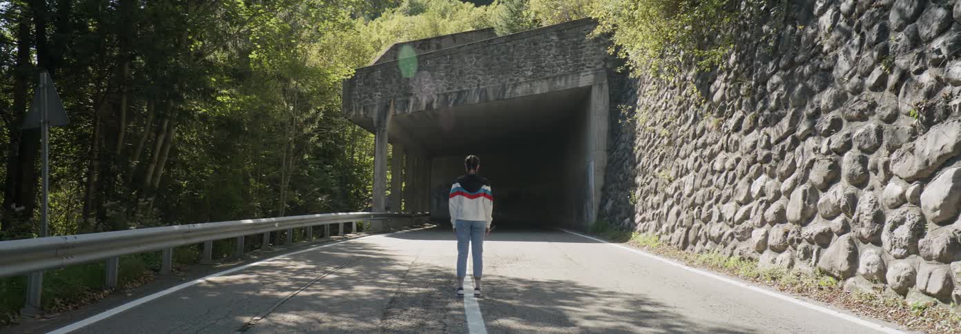 A woman is standing in front of a tunnel