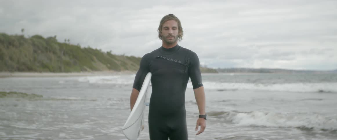 A man stands in the water with a surfboard