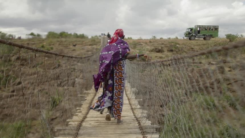 A person in robes crosses the rope bridge