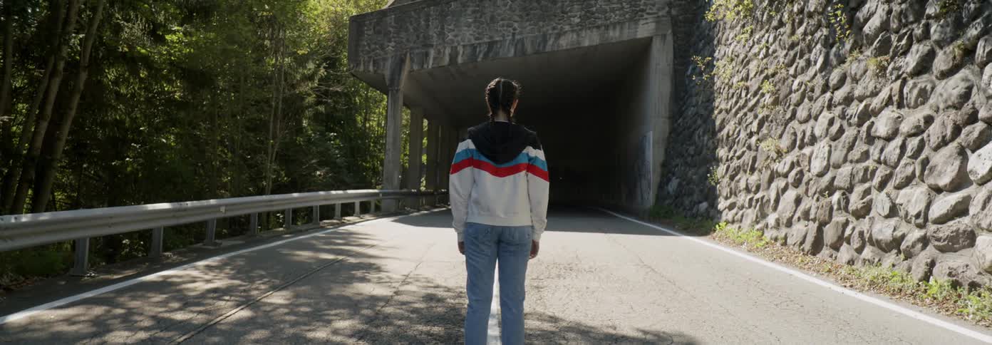 A woman stops before a long tunnel on the road