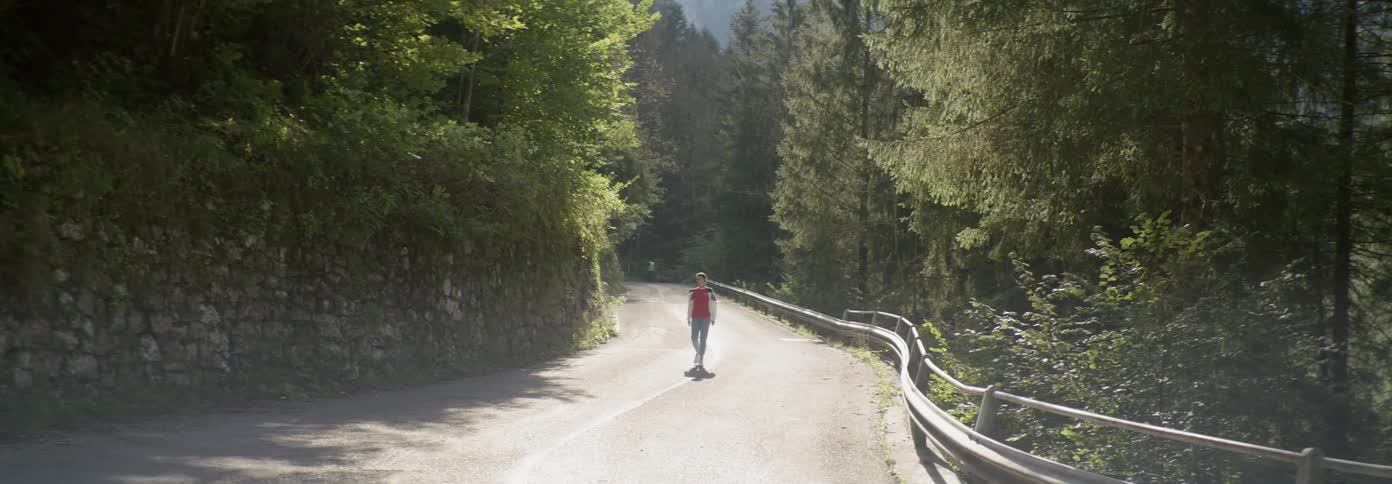 A woman is slowly walking down the middle of the road