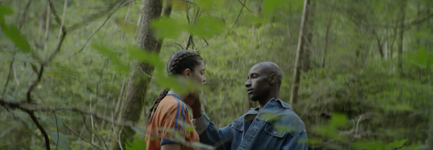 A man and woman have an intimate moment in the woods