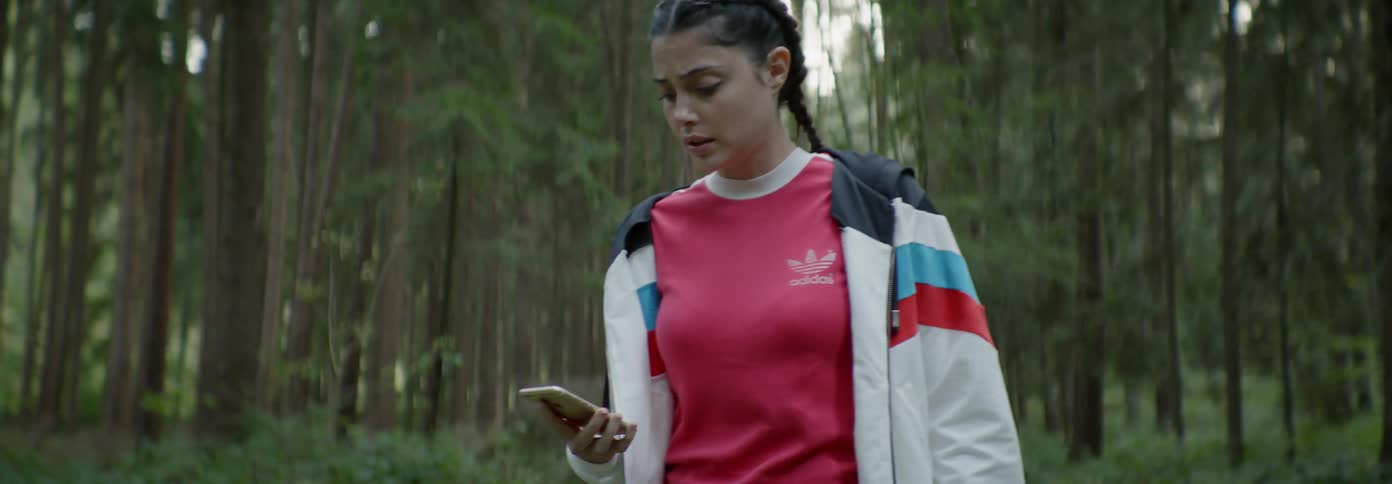 Scared looking girl looks around at the woods and at her phone
